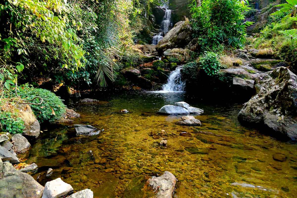 33 Waterfalls cascading across rock terraces with lush greenery near Munnar